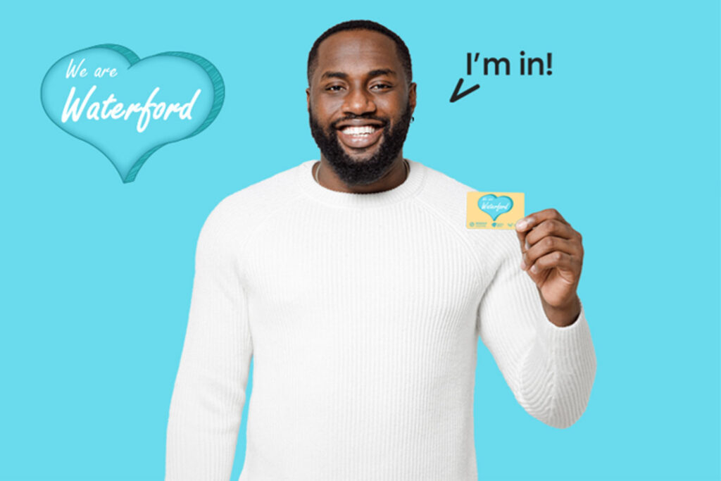 I'm in! Campaign. Young african man holding a WE ARE Waterford card.